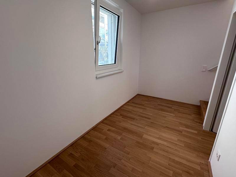 Kleiner, heller Raum mit Holzboden und Fenster, ideal als Kinder- oder Arbeitszimmer.