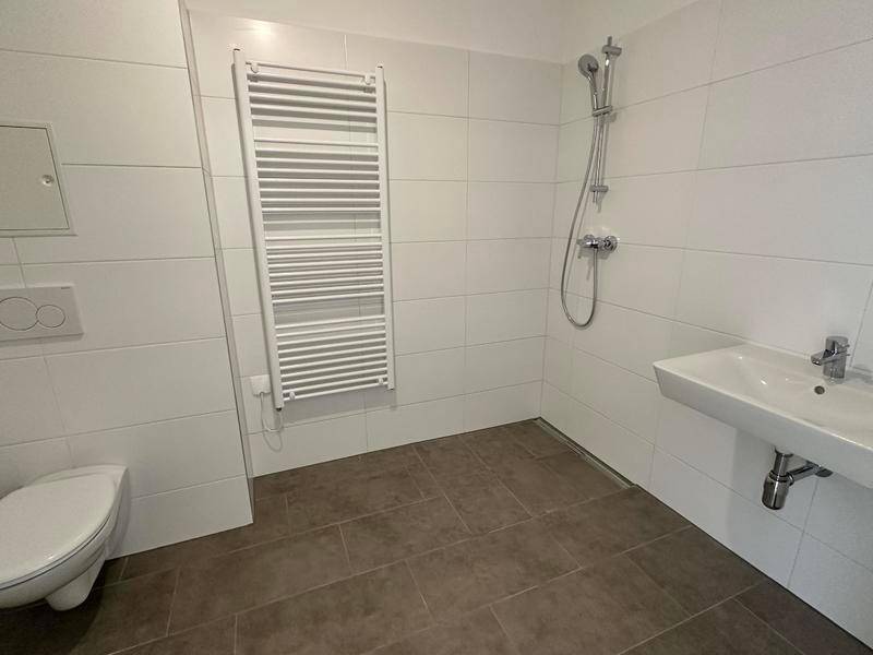 Funktionales Badezimmer mit Dusche, WC, Waschbecken und praktischem Handtuchheizkörper.