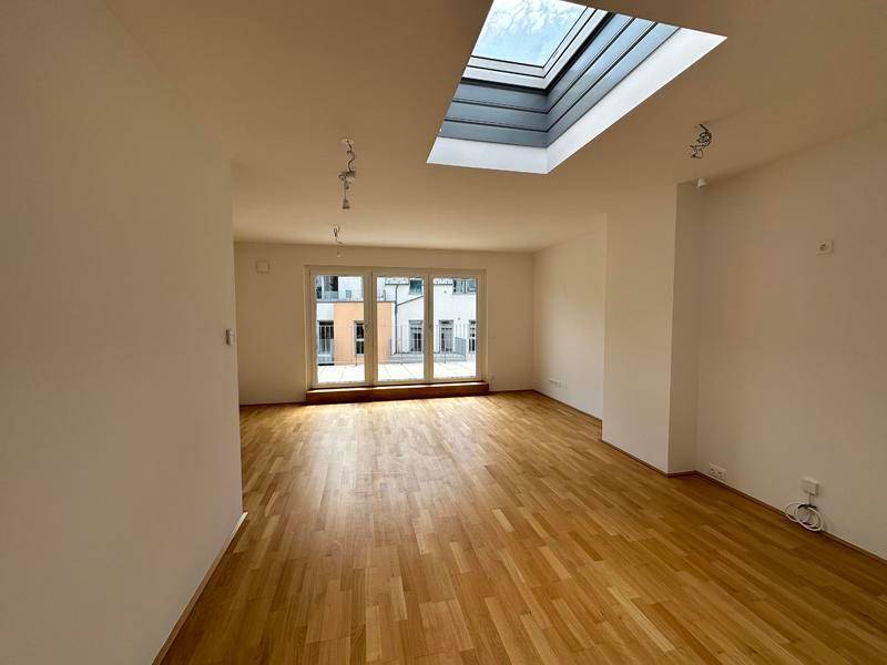 Geräumiger Wohnbereich mit Holzboden, großen Fenstern und einem modernen Dachfenster.