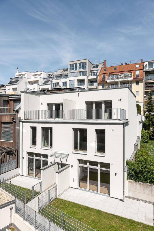 Moderne Wohnanlage mit weißer Fassade, großen Fenstern und Dachterrassen.