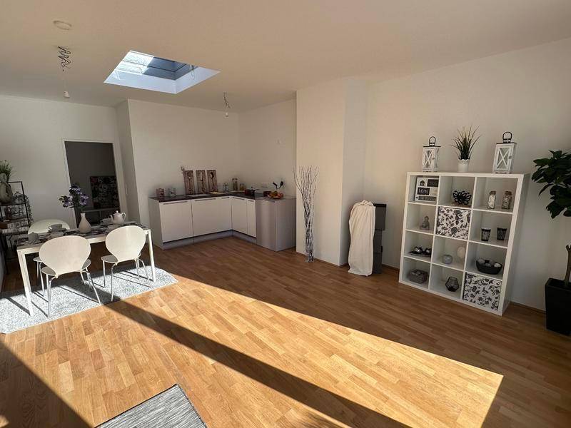 Offener Wohn-Essbereich mit Holzboden, kleiner Küchenzeile und Dachfenster.