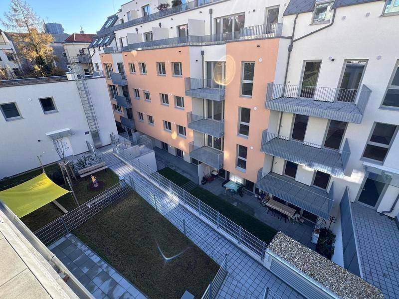 Innenhof einer modernen Wohnanlage mit Grünflächen, Terrassen und Balkonen.