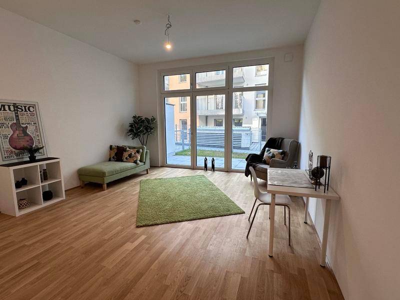 Helles Wohnzimmer mit Holzboden, großen Fenstern und Zugang zu einer Terrasse.