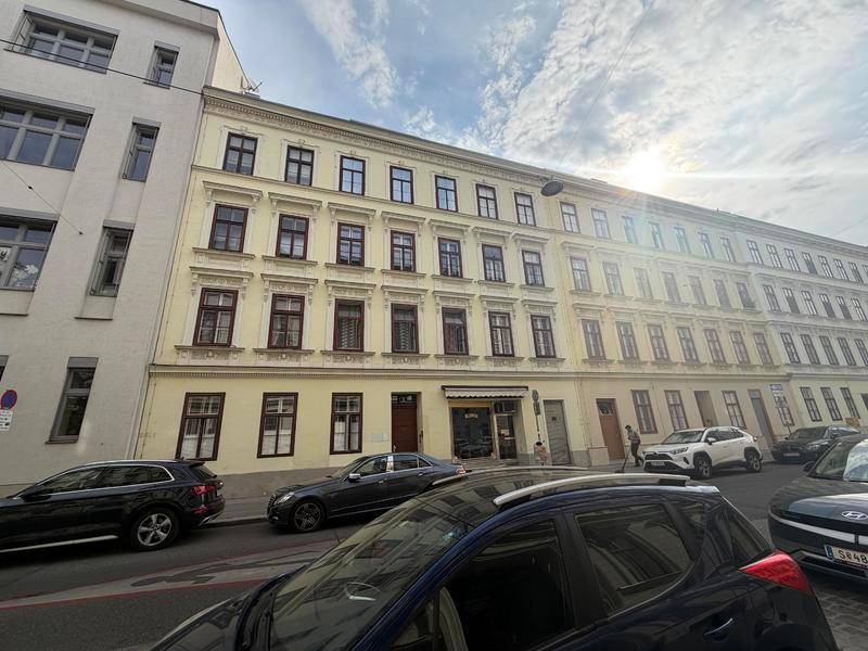 Historisches Mehrfamilienhaus mit klassischer Fassade und vielen Fenstern an einer Straße.