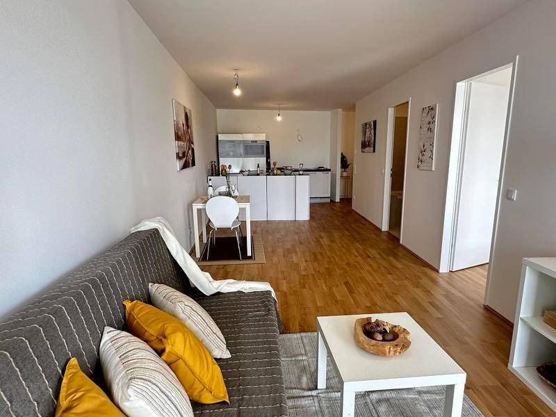 Geräumiger offener Wohnbereich mit Holzboden, Sofa und Essbereich, angrenzend an die Küche.
