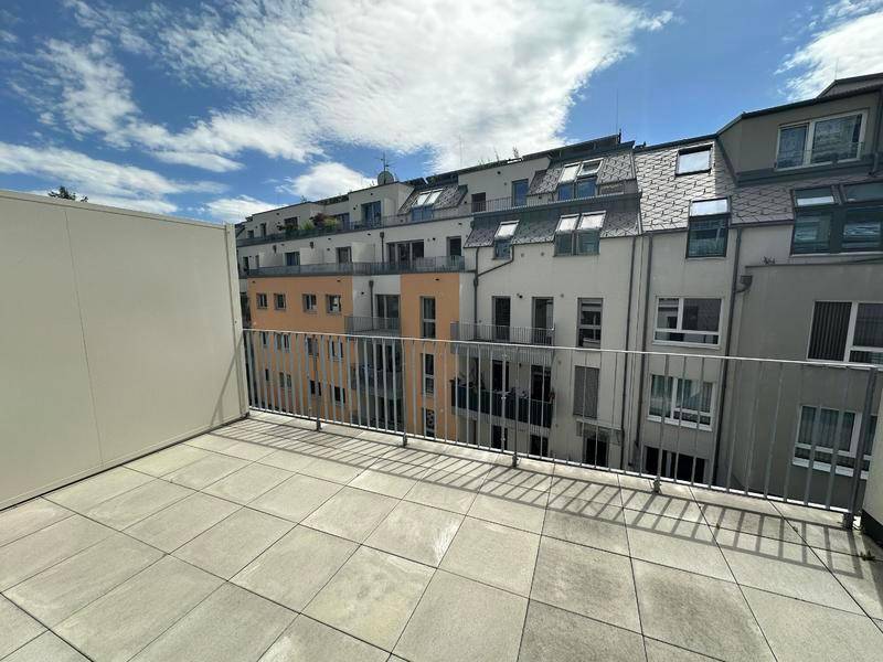 Geräumiger Balkon mit Fliesenboden und Blick auf die umliegenden modernen Wohngebäude.