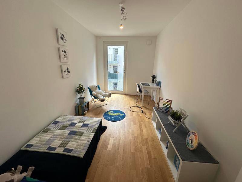 Kinderzimmer mit Holzboden, Einzelbett und großem Fenster für viel Tageslicht.