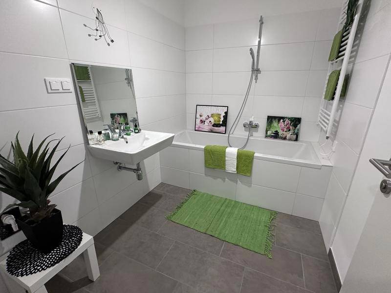Modernes Badezimmer mit Badewanne, Waschbecken und weißen Fliesen an den Wänden.