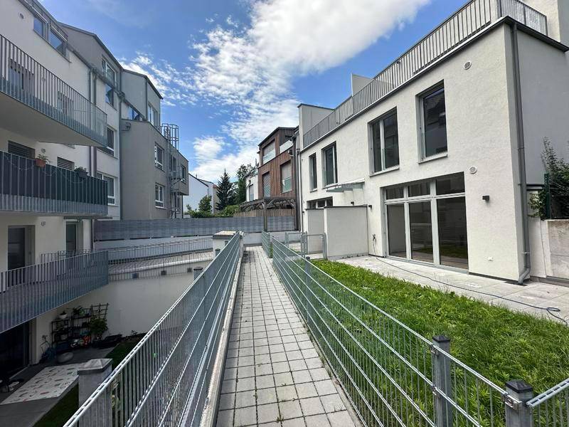 Barrierefreie Rampe zwischen modernen Wohngebäuden mit Grünflächen, sorgt für einfachen Zugang.