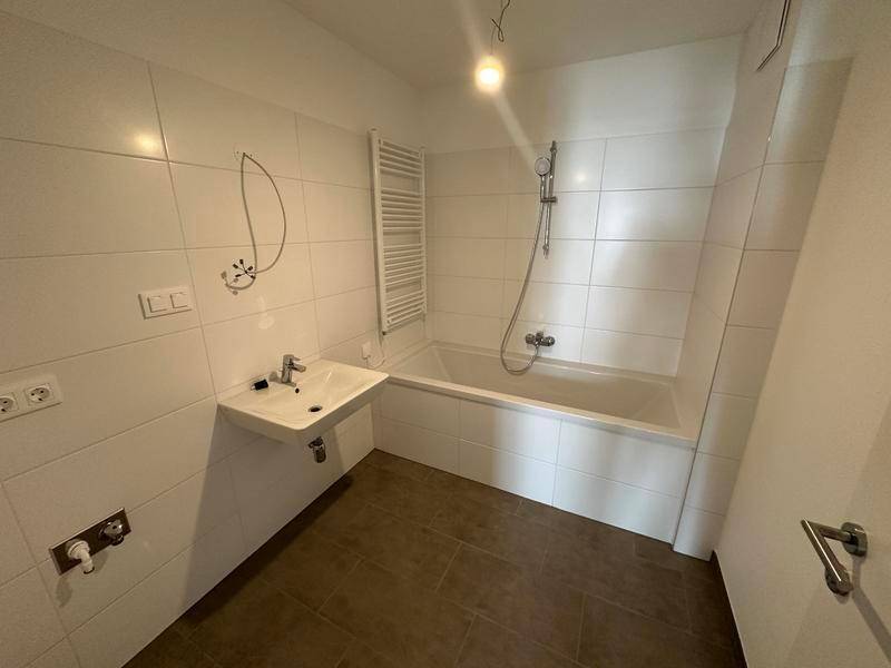 Modernes Badezimmer mit Badewanne, Waschbecken und beheiztem Handtuchhalter.