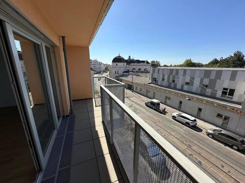 Langer Balkon mit Metallgeländer und Blick auf die Straße und städtische Gebäude.