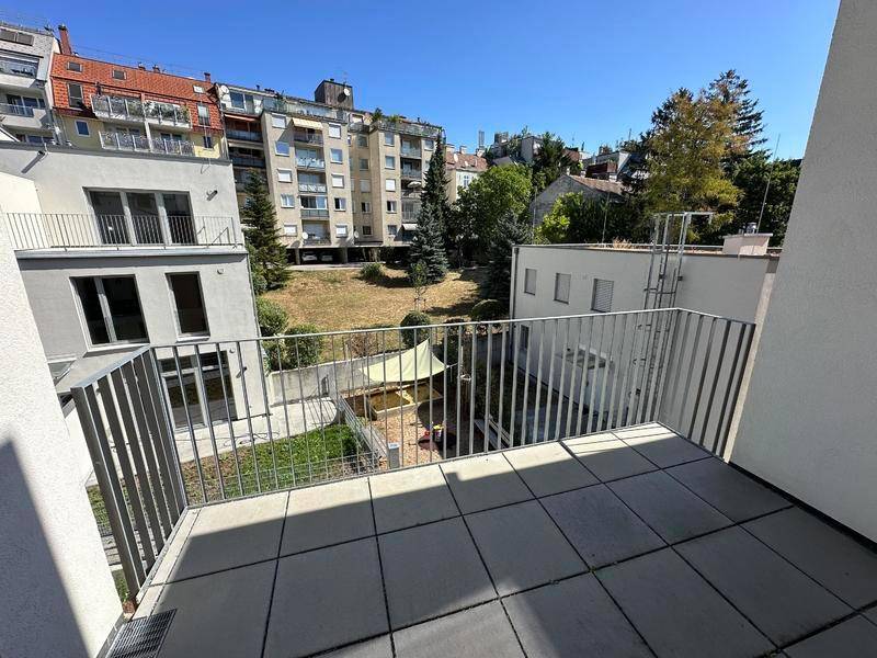 Geräumiger Balkon mit Fliesen und Blick auf den gemeinschaftlichen Gartenbereich.