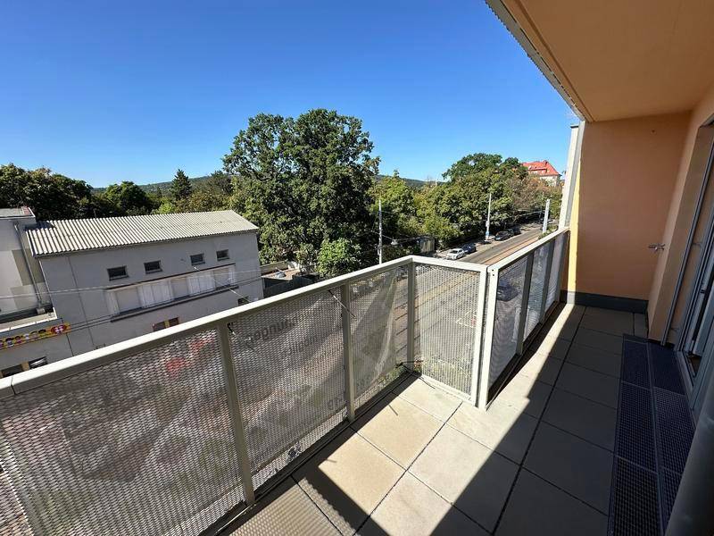 Heller Balkon mit Gittergeländer und weitem Blick auf Bäume und die Stadt.