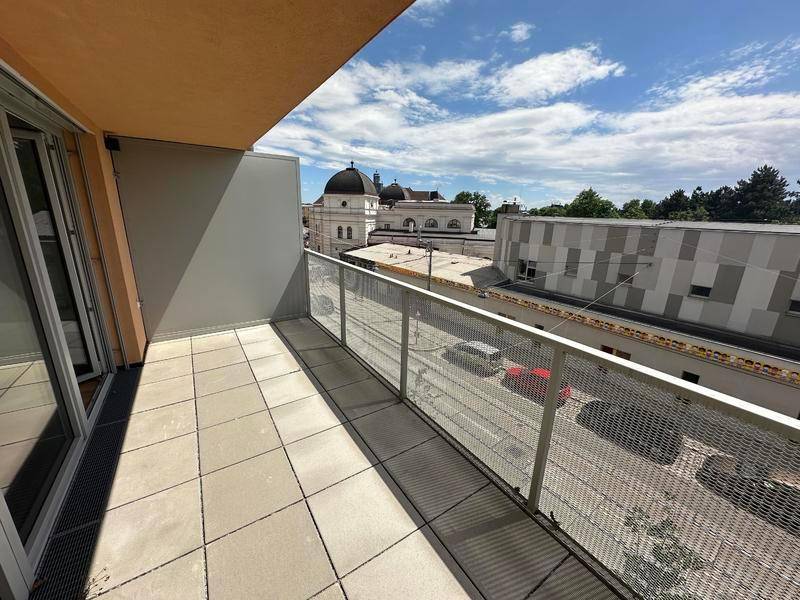 Heller Balkon mit Fliesenboden und Metallgeländer, bietet einen weiten Blick über die Umgebung.