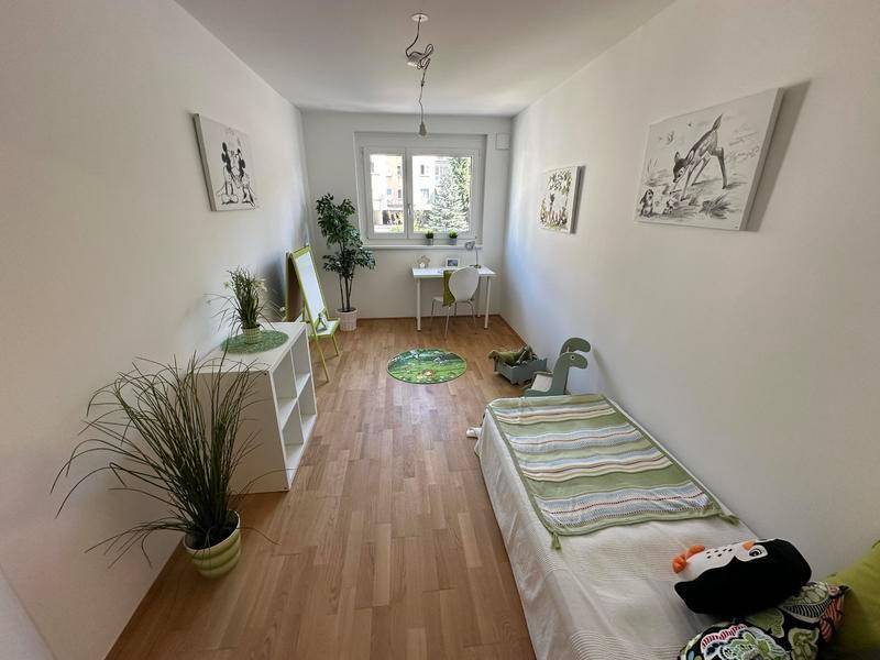 Helles Kinderzimmer mit Holzboden, Schreibtisch und kindgerechter Dekoration.