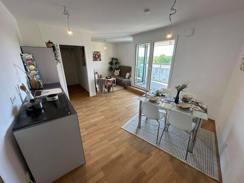 Offener Wohn- und Essbereich mit kleiner Küchenzeile und Zugang zum Balkon, hell und modern eingerichtet.