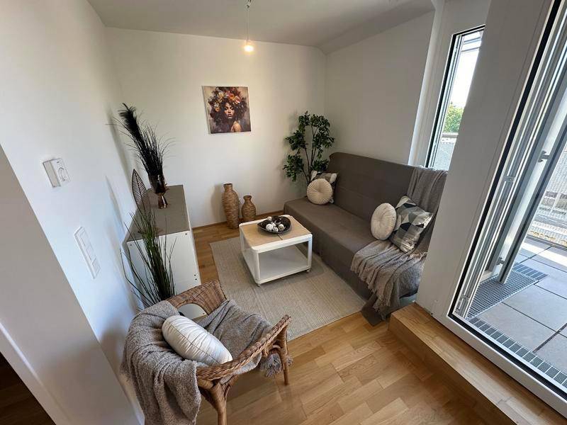 Gemütlicher Wohnbereich mit Sofa und Couchtisch, hell durch große Balkontüren, modern dekoriert.