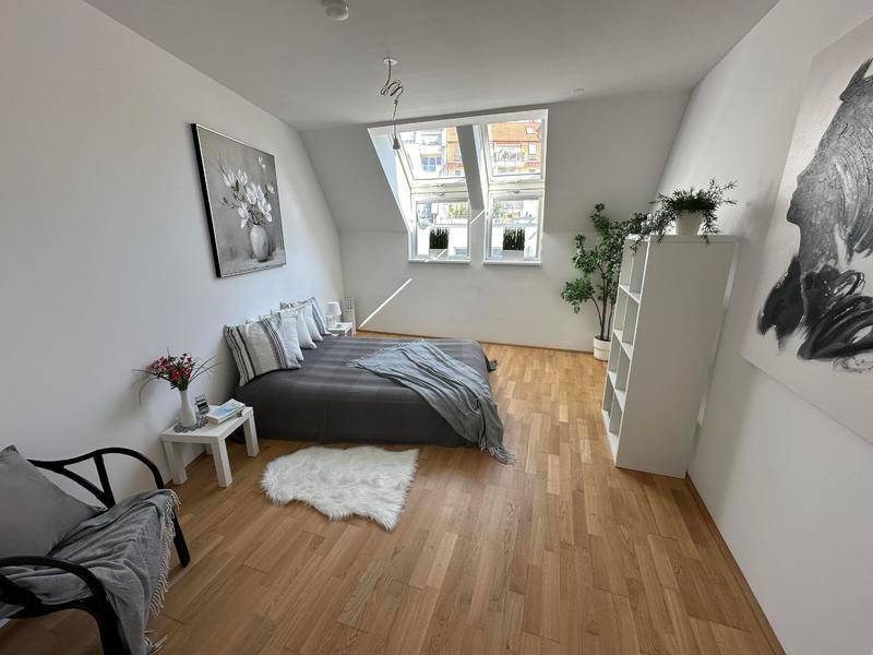 Geräumiges Schlafzimmer mit Holzboden, Dachschrägen und Dachfenstern, hell und modern gestaltet.