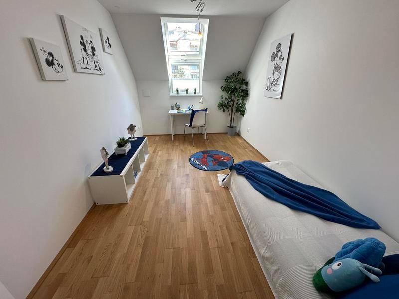 Kinderzimmer mit Holzboden, Dachschrägen und Dachfenster, hell und freundlich eingerichtet.