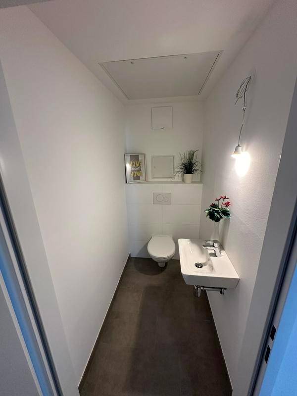 Kleines Gäste-WC mit Wand-WC und Waschbecken, minimalistisch und funktional gestaltet.