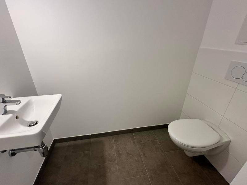 Separates Gäste-WC mit wandhängender Toilette und kleinem Waschbecken.