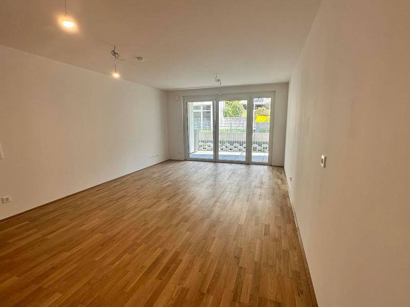 Lichtdurchfluteter Raum mit Holzboden und großen Schiebetüren zur Terrasse.