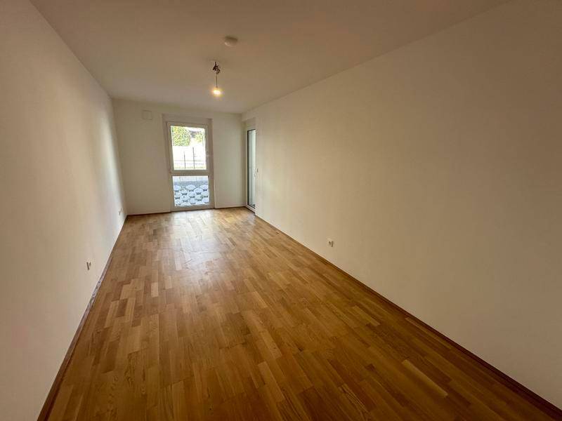 Schlafzimmer mit Parkettboden und Fensterfront zum Außenbereich für viel Tageslicht.