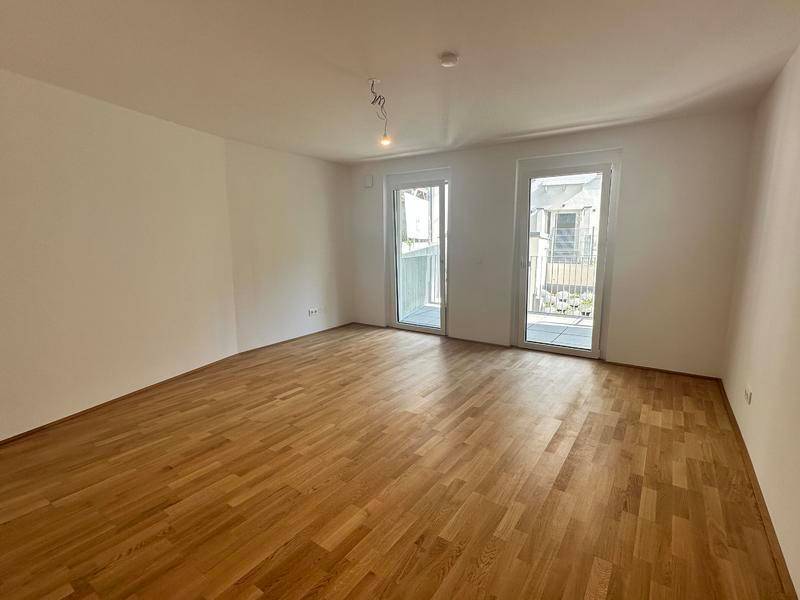 Helles Schlafzimmer mit Parkettboden und zwei Zugängen zu Außenbereichen.
