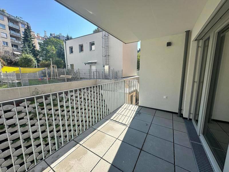 Helle Terrasse mit modernem Metallgeländer und Ausblick auf die benachbarten Gebäude.