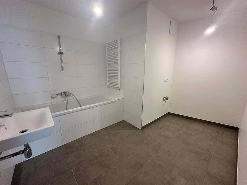 Modernes Badezimmer mit Badewanne, Waschbecken und weiß gefliesten Wänden.
