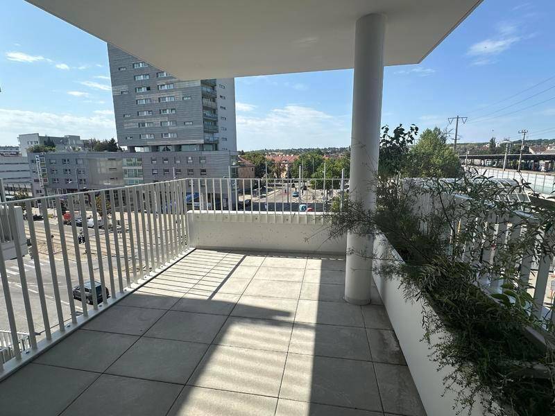 Geräumiger Balkon mit Fliesenboden und Blick auf die Stadt und umliegende Gebäude.