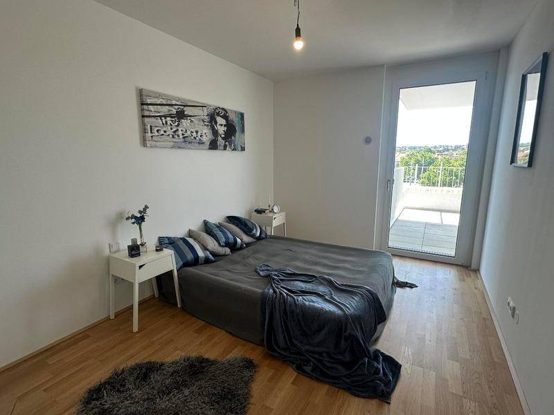 Schlafzimmer mit Holzboden, Doppelbett und Zugang zu einem Balkon.