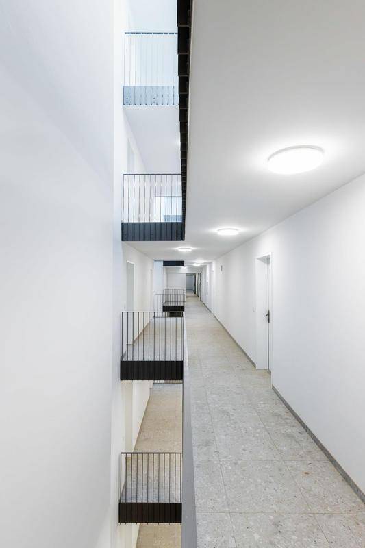 Heller Flur im Mehrfamilienhaus mit modernen Leuchten und Zugang zu den Wohnungen.