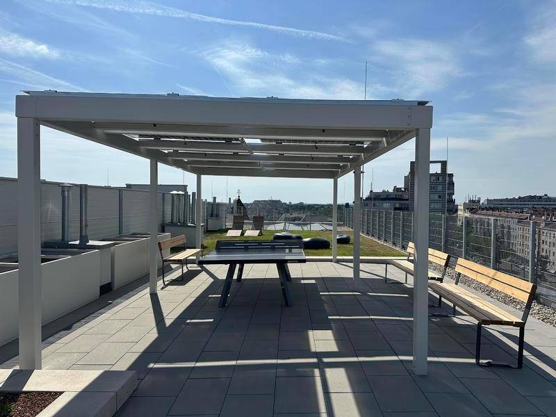 Überdachter Bereich auf der Dachterrasse mit Tischtennisplatte und Bänken.