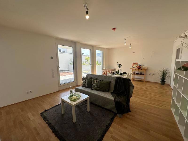 Heller offener Wohn- und Essbereich mit Holzboden und Zugang zur Terrasse.