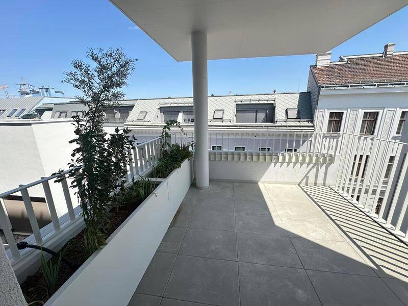 Überdachter Balkon mit Fliesenboden und Pflanzenkübeln, bietet einen Blick auf die Umgebung.