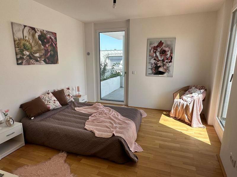 Gemütliches Schlafzimmer mit Holzboden, viel Tageslicht und Zugang zu einem Außenbereich.