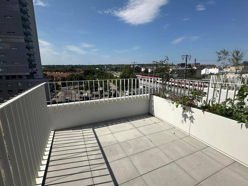 Geräumige Terrasse mit Fliesenboden und Pflanzenkübeln, bietet einen weiten Blick über die Stadt.