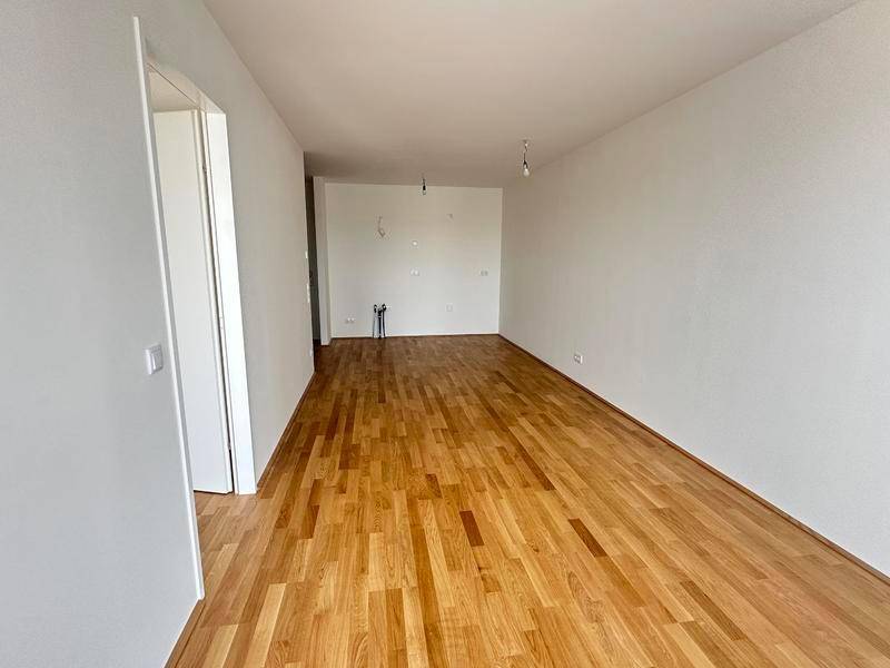 Leeres Zimmer mit hellem Holzboden und weißen Wänden, bereit für die individuelle Gestaltung.