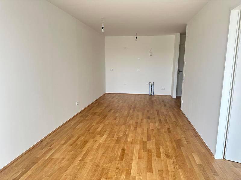 Geräumiger, heller Raum mit Holzparkett und weißen Wänden, bereit zur Einrichtung.