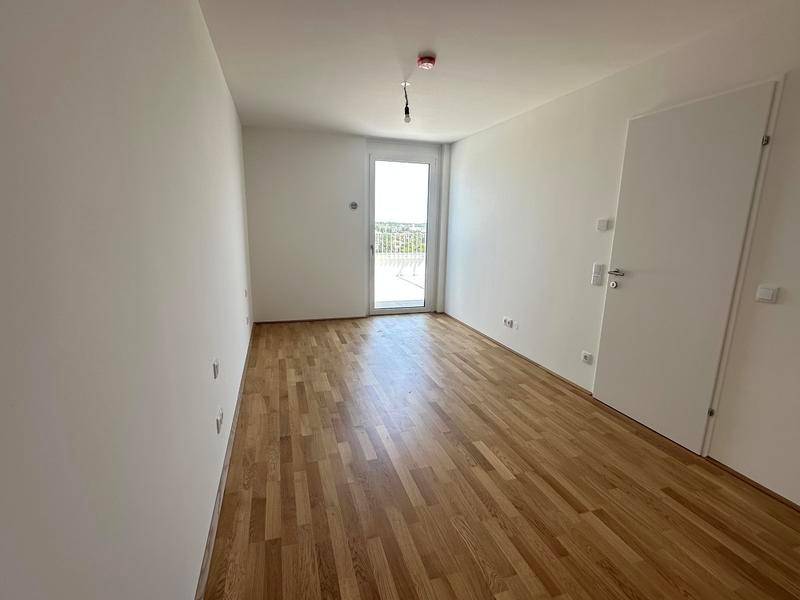 Schlafzimmer mit Parkettboden und Zugang zu einem Balkon oder einer kleinen Terrasse.