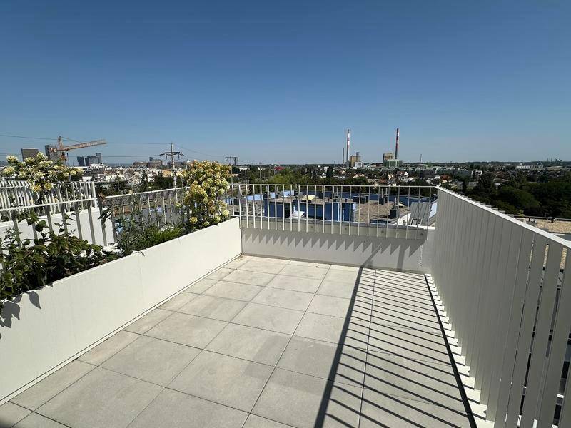 Geräumige Dachterrasse mit Fliesenboden, modernen Pflanzgefäßen und Panoramablick über die Stadt.