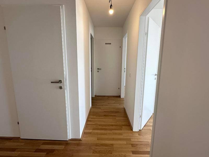 Heller Flur mit Holzboden und mehreren weißen Türen, die zu den angrenzenden Räumen führen.
