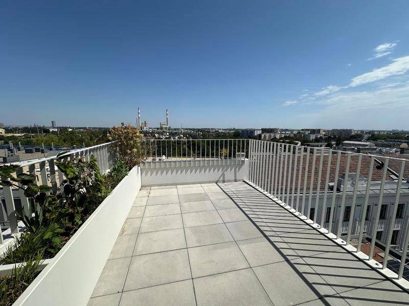 Weitläufige Dachterrasse mit Fliesenboden und Panoramablick über die Stadt und Industrieanlagen.