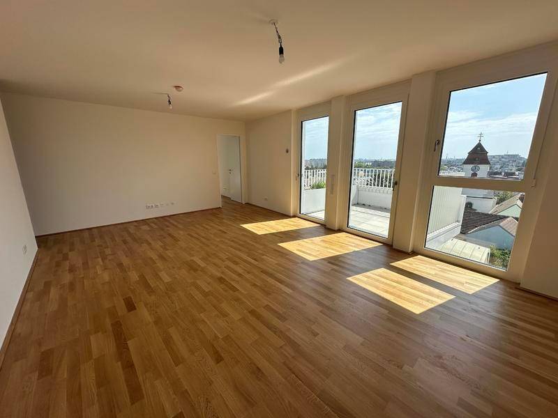 Lichtdurchfluteter Wohnbereich mit Holzboden und großen Fenstern, die viel Tageslicht hereinlassen.
