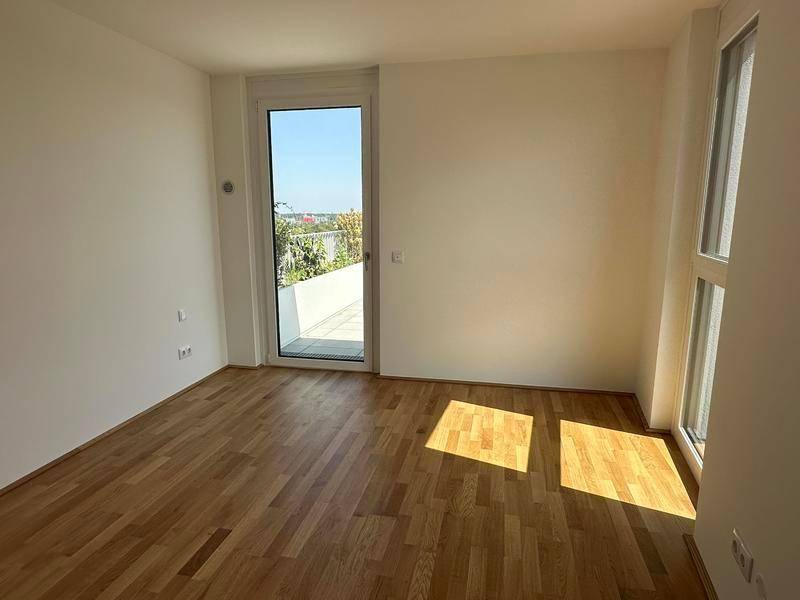 Helles Zimmer mit Holzboden und Zugang zu einem kleinen Außenbereich, ideal als Schlafzimmer.