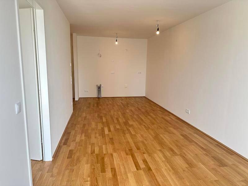 Leerer Raum mit Parkettboden und weißen Wänden, vorbereitet für Installationen.