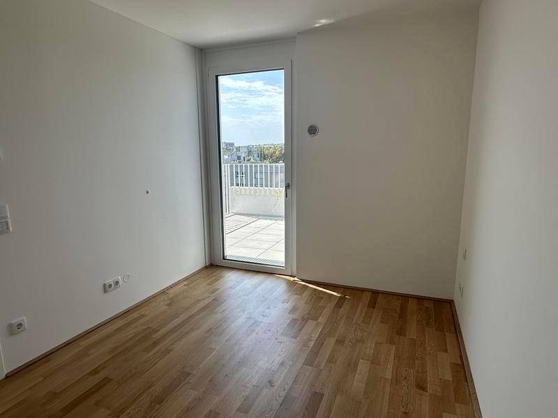 Helles Zimmer mit Parkettboden und direktem Zugang zu einem Außenbereich.