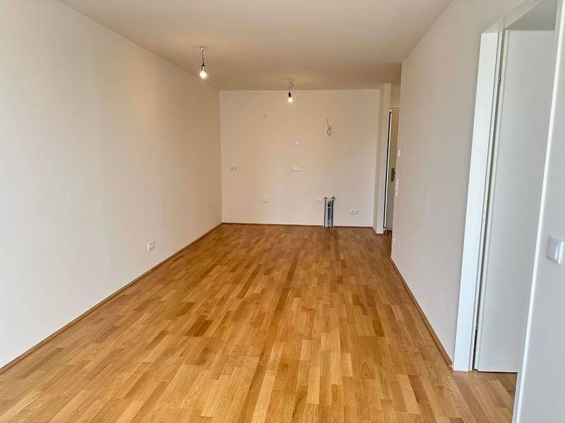 Großer, heller Wohnbereich mit Parkettboden und weißen Wänden, ideal für individuelle Einrichtung.