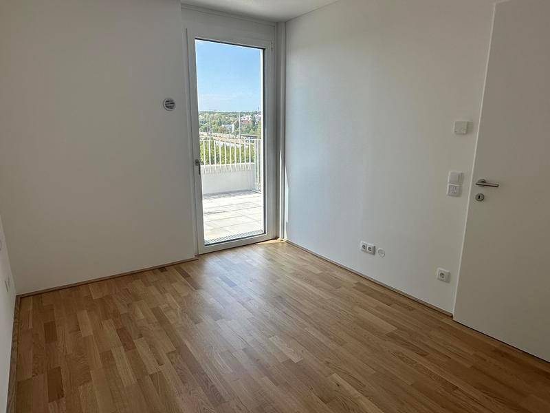 Lichtdurchflutetes Schlafzimmer mit Holzboden und direktem Zugang zu einem privaten Balkon.